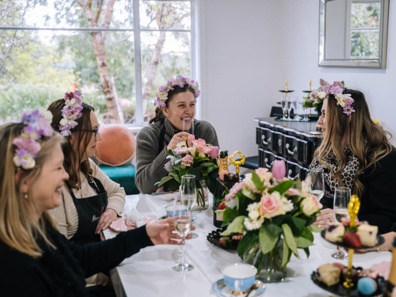 A group of women smiling and laughing wearing flower crowns